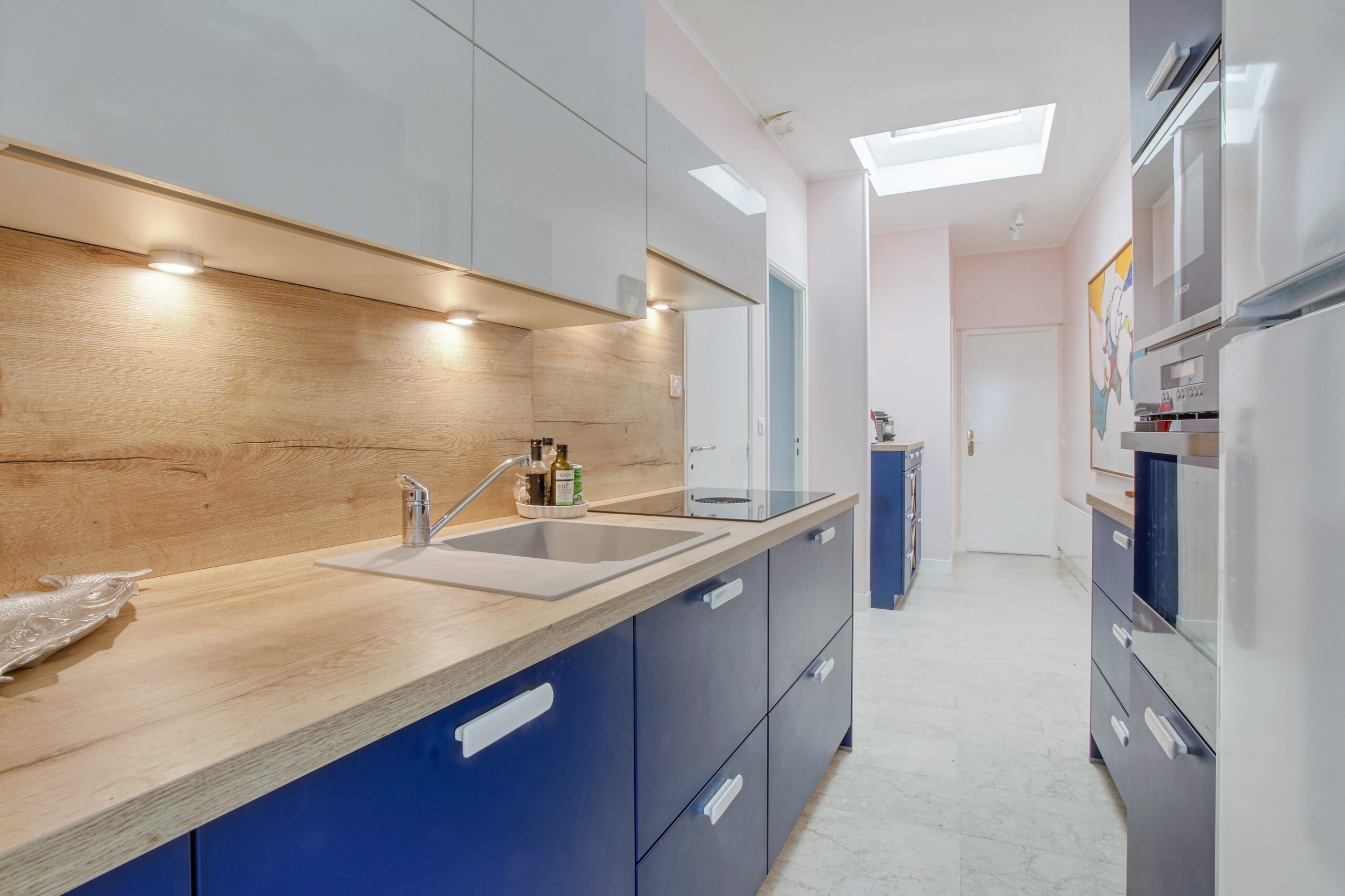 Cuisine Bleu : les deux côtés équipés encadrent le passage central.