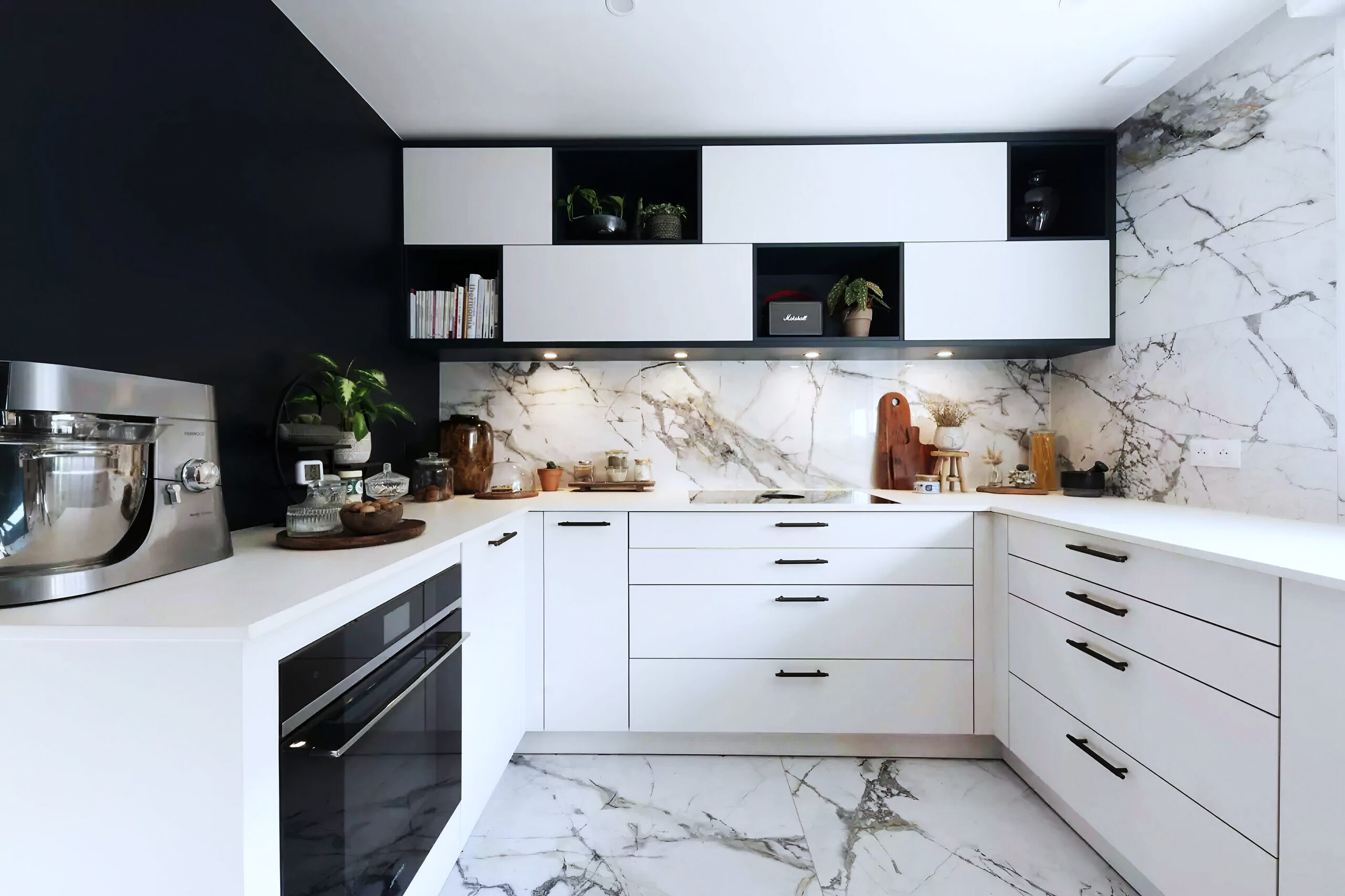 Cuisine Blanc noir : les surfaces murales se raccordent au plan sur les trois côtés de la cuisine.