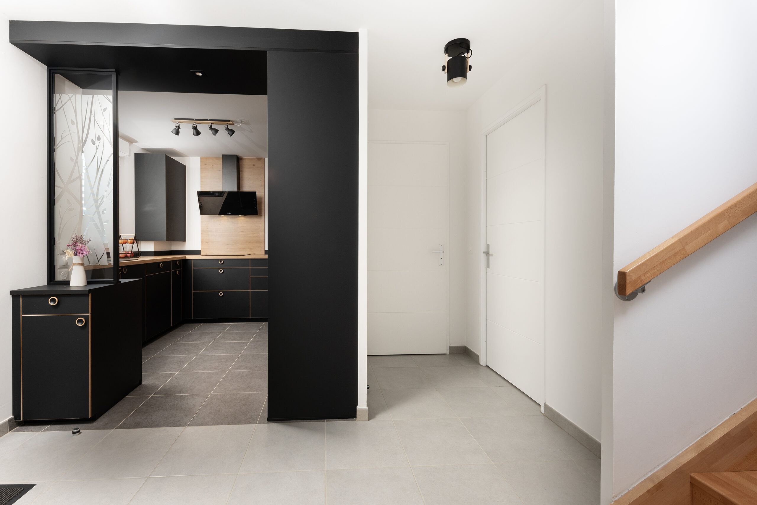 Cuisine Noire et bois : l’entrée de la cuisine est en relation directe avec le couloir et l’escalier.
